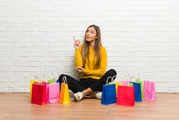 Young girl with lot of shopping bags pointing a great idea and looking up