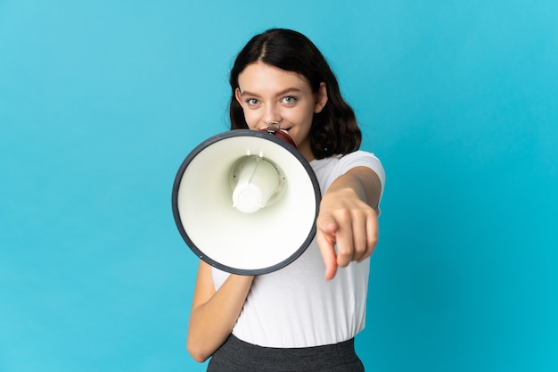 Young girl with loudspeaker on blue