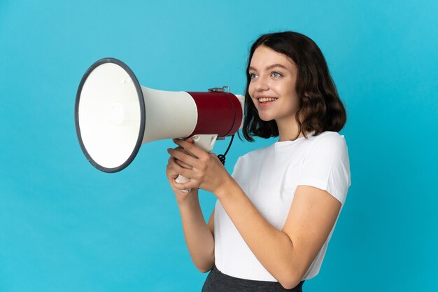 Young girl with loudspeaker on blue