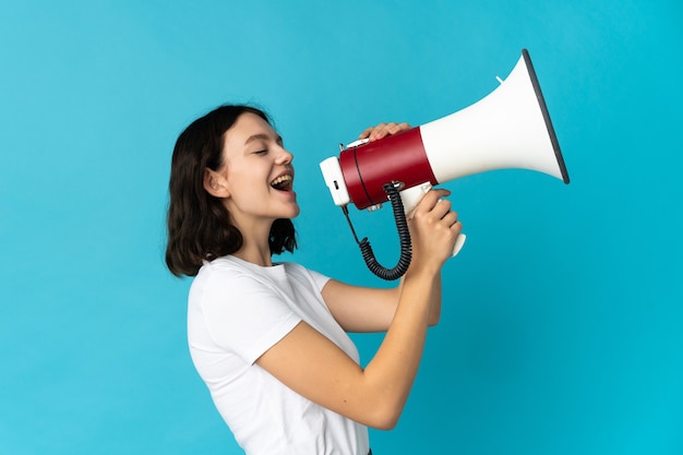 Young girl with loudspeaker on blue