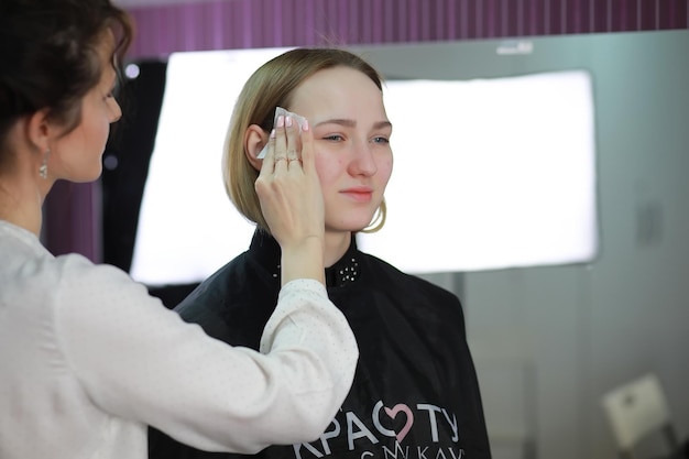 Young girl with a make-up artist in the studio in front of a mirror