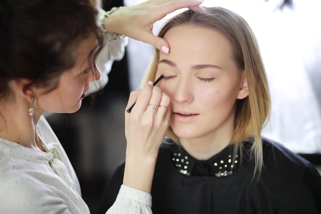 Ragazza con un truccatore in studio davanti a uno specchio