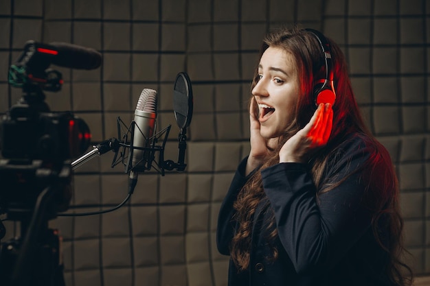 Young girl with microphone and headphones in recording studio\
recording of vocal blogger reading text voice acting