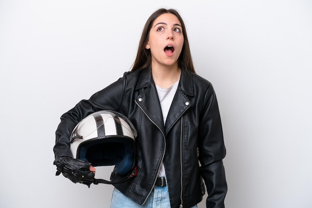 Young girl with a motorcycle helmet isolated on white\
background looking up and with surprised expression