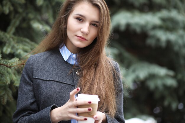 屋外でコーヒーの紙コップを持つ少女