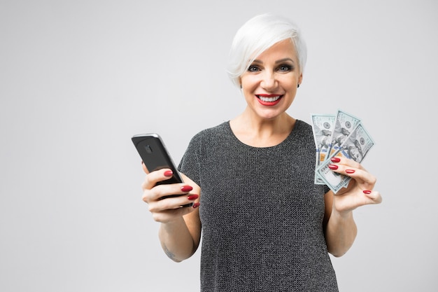 Young girl with a phone and a fan of dollars in her hands stands on a light