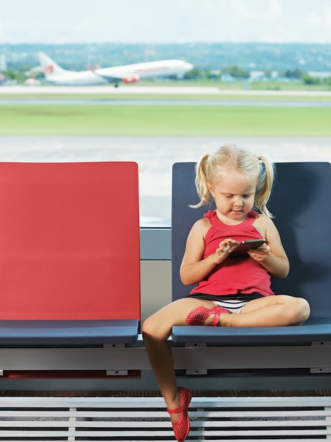 Foto ragazza giovane con il telefono in mano in attesa del volo in aeroporto