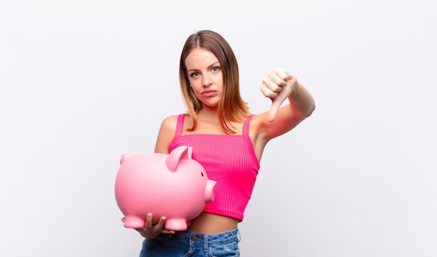 young girl with a piggy bank showing thumbs down