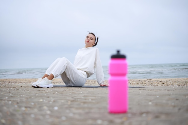 Young girl with pink water bootle on the bech High quality photo