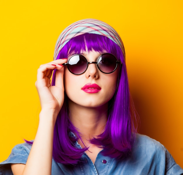 Young girl with purple hair and sunglasses on yellow