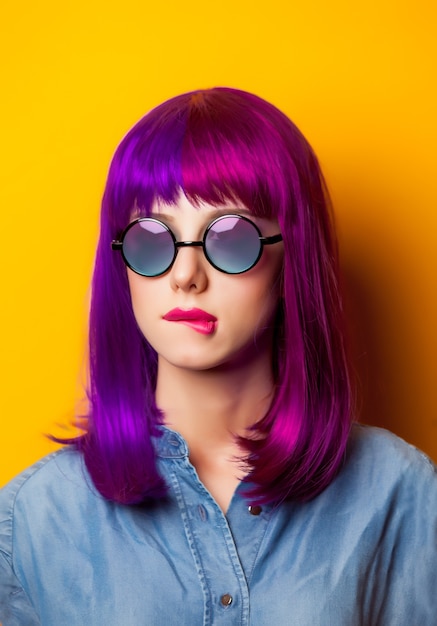 Young girl with purple hair and sunglasses on yellow