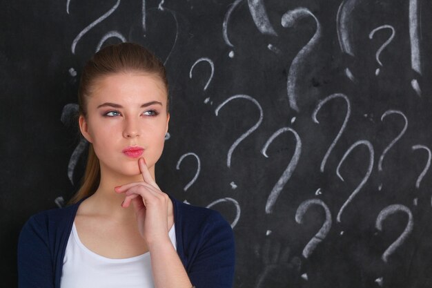 Young girl with question mark on a gray background .