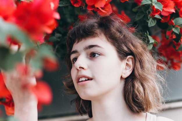 Young girl with red flowers. Perfume and organic cosmetic. Natural beauty