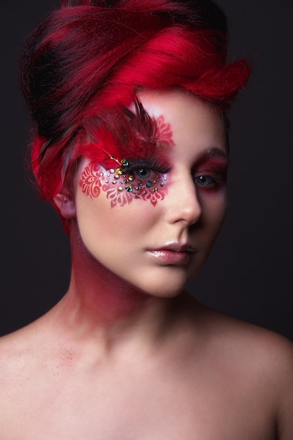 Молодая девушка с рыжими волосами и творческим гениальным макияжем