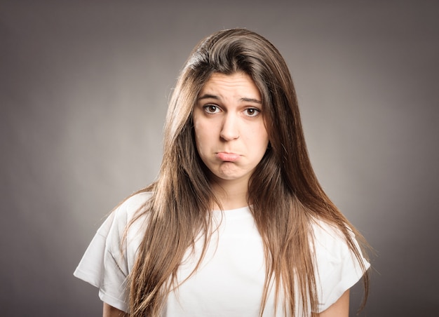 Young girl with sad expression on gray 