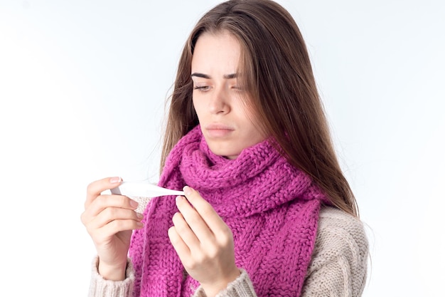 A young girl with a scarf around his neck holding the thermometer and the looks temperature close-up