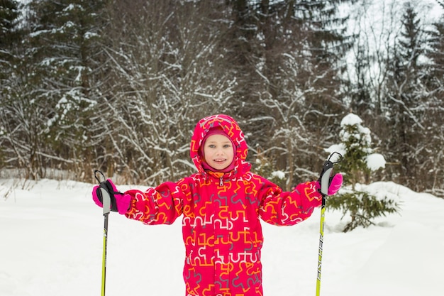 Young girl with ski in the snow forest