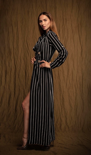 young girl with a slim figure in a black and white striped dress full growth