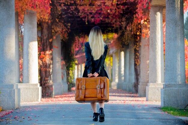 Young girl with suitcase in red grapes alley