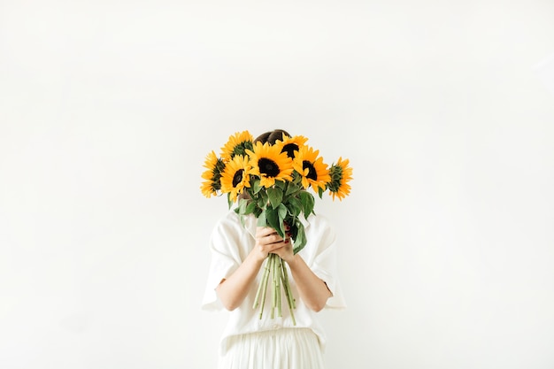 Young girl with sunflowers bouquet in hands on white