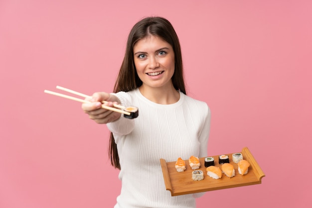 Foto ragazza con i sushi sopra il rosa isolato