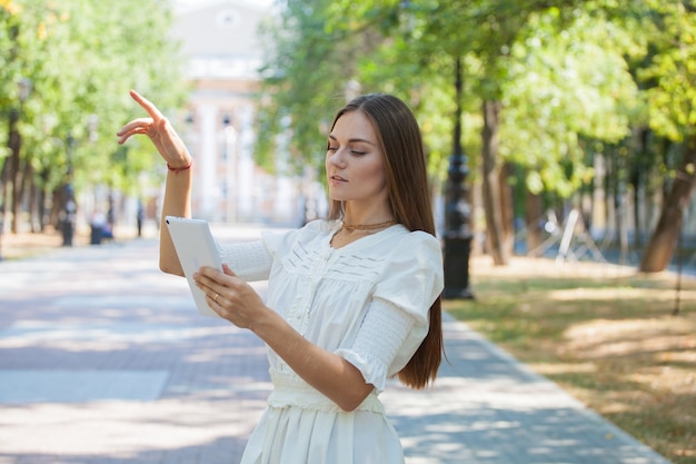 A young girl with a tablet in her hands on the background of an old building