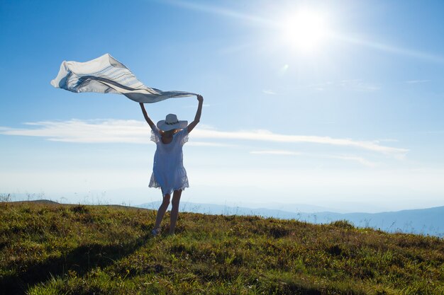 Ragazza con un fazzoletto sollevato, che si gode la luce del sole in cima alla montagna