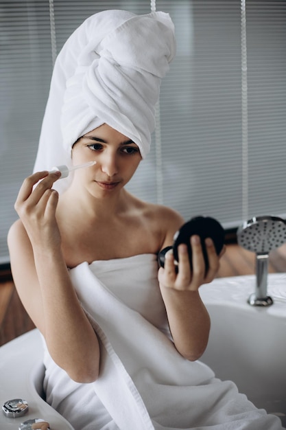 Young girl with towel on her head makes facial treatments Skin care moisturizing with serum