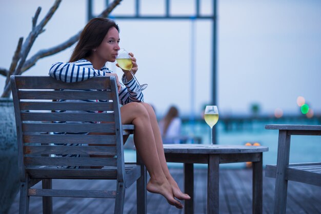 Young girl with white wine at evening outdoor cafe