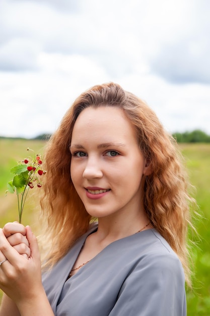 Young girl with wild strawberries in summer day