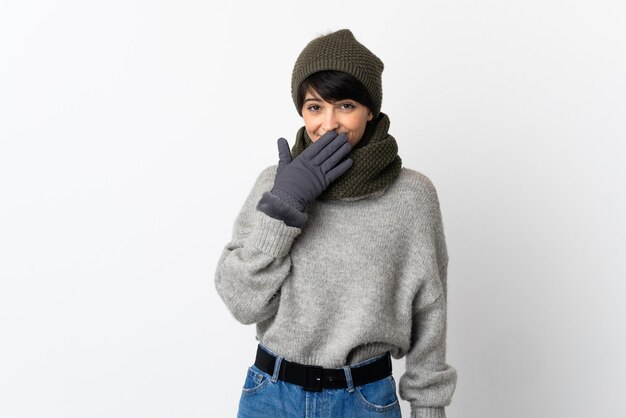 Young girl with winter hat happy and smiling covering mouth with hand