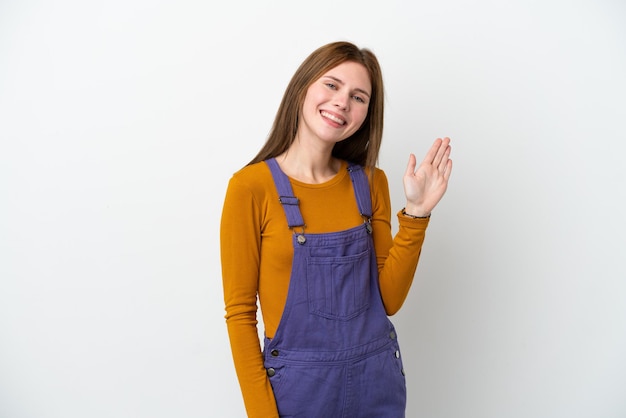 Young girl with winter hat isolated on blue background pointing up and surprised