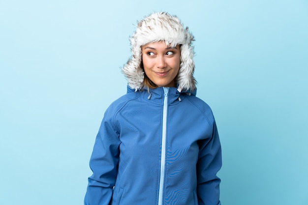 Young girl with winter hat isolated on blue standing and looking to the side