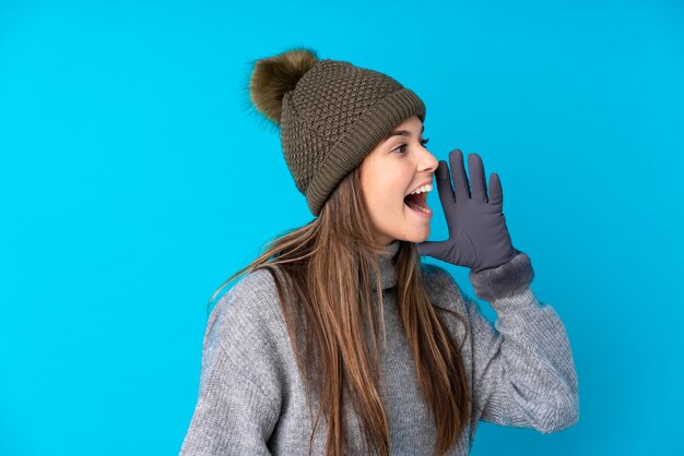 Молодая девушка в зимней шапке на изолированной стене