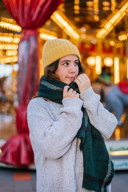 クリスマスフェアで黄色のウールのキャップとスカーフを持つ少女