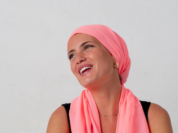 癌に苦しんだ後、彼女の髪にピンクのスカーフを持つ若い女の子の女性