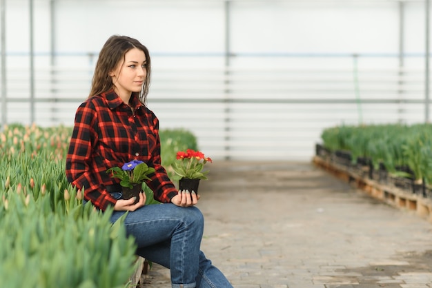 若い女の子、温室の花を持つ労働者
