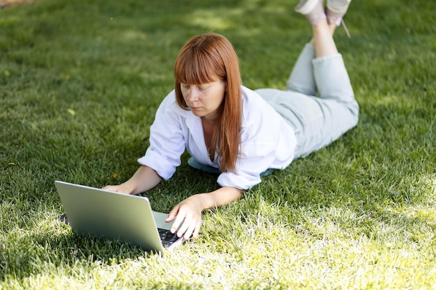 公園でコンピューターに取り組んでいる少女