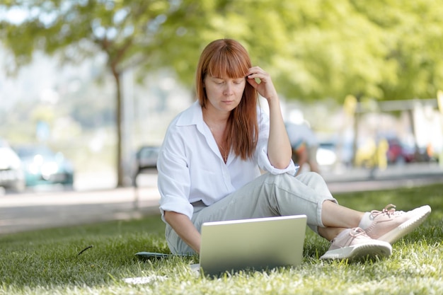 Young girl working on a computer in the park