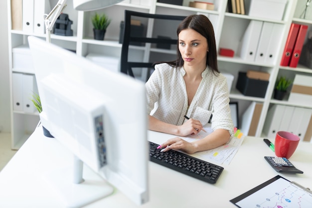 A young girl working in the office with documents and a computer. 