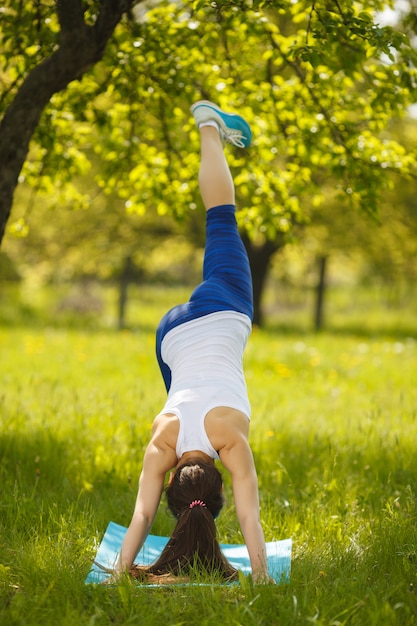 Ragazza che risolve all'aperto. bella donna che fa esercizi di pilates, yoga e fitness sulla natura.