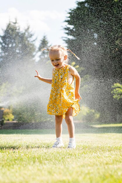 Photo a young girl in a yellow dress sprinkles a golf course.