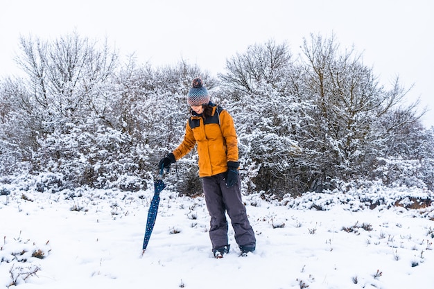 Young girl in yellow jacket playing in the snow with an umbrella. Snow in the town of Opakua near Vitoria in Araba