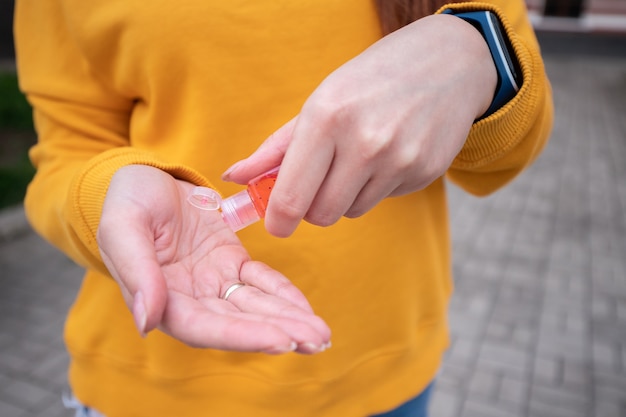 A young girl in a yellow sweater disinfects the hands with an antiseptic