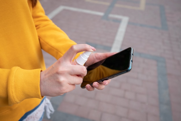 Young girl in a yellow sweater holds a smartphone on the street