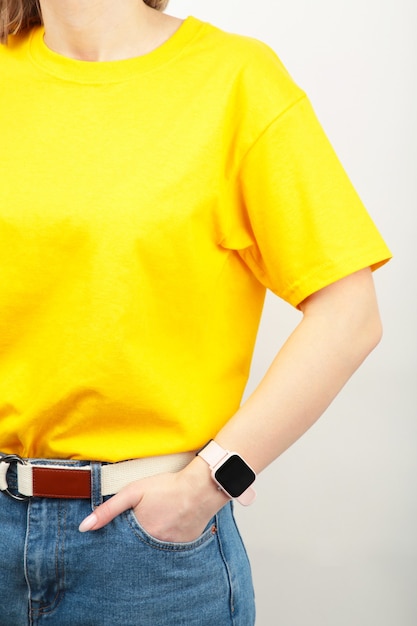 Молодая девушка в желтой футболке на серой поверхности