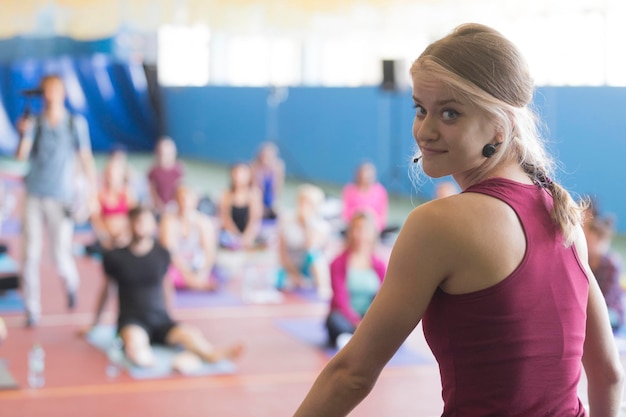 Young girl yoga trainer conducts a lesson with a group of students