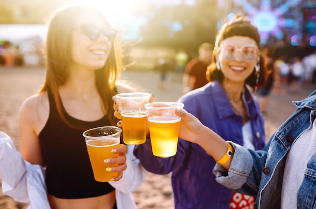 Young girlfriends drinking beer having fun at music festival Friendship celebration Beach party