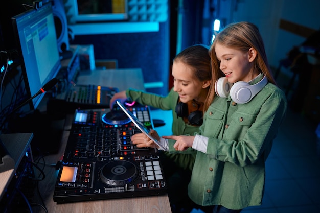 Молодые девушки регулируют звук на звуковом микшере на радиостанции