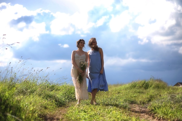 Young girls are walking in the field before the rain